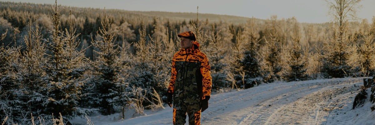 Hunter in SwedTeam blaze camo standing on a snowy forest track among frosted spruce trees