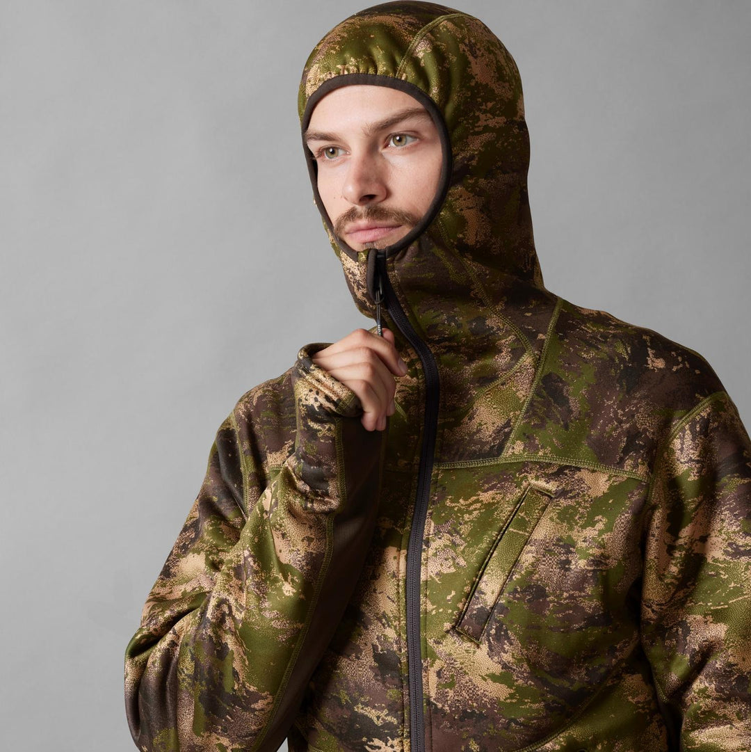 Model wearing the Härkila Deer Stalker camo fleece hoodie with the hood up, three-quarter view zipping the front closed