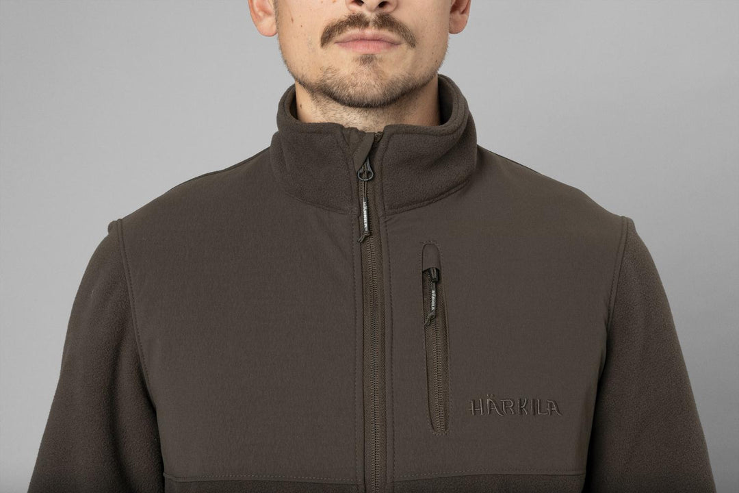 Close-up on a model: chest and collar of the olive fleece, front-on, with logo embroidery above the hem