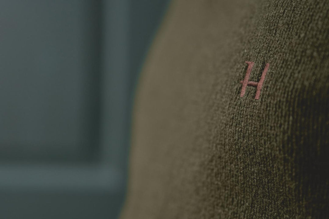 Harkila Vincent merino v-neck pullover in rosin green – view 9: close-up of the embroidered H emblem on the chest