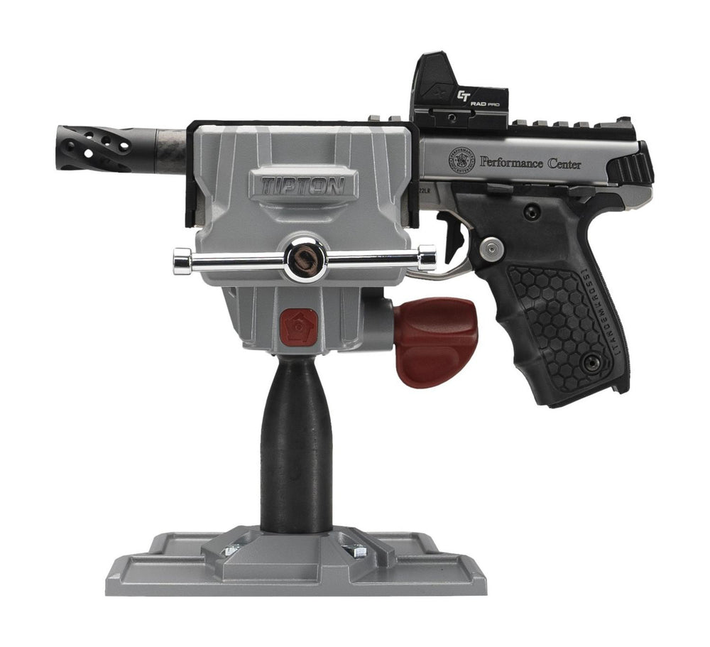 Tipton Best Gun Vise 360 rotated to a three-quarter angle, the grey head and red jaws holding a black Performance Center pistol above the pedestal post and grey base