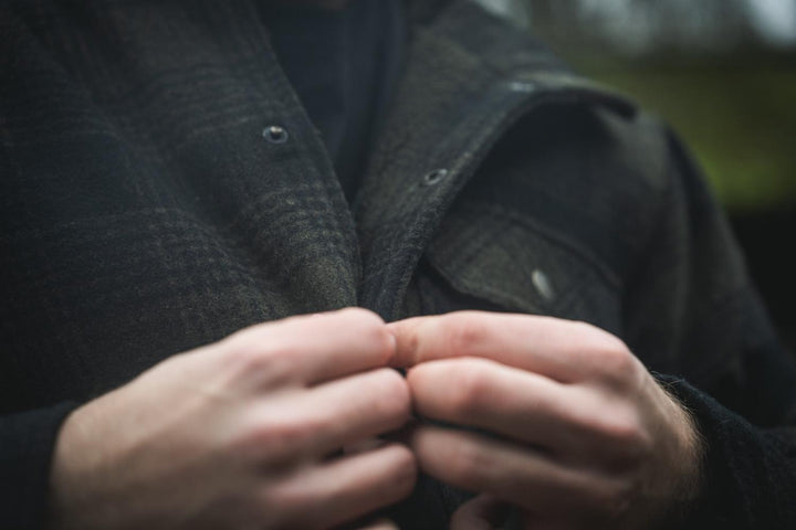 Close-up of a wearer's hands fastening the press-stud front of the Seeland Canada Yukon jacket