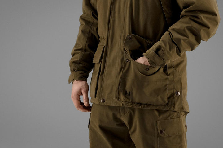 Detail of the Härkila Retrieve jacket hip, a hand slipped into the handwarmer pocket behind the lower flap pocket