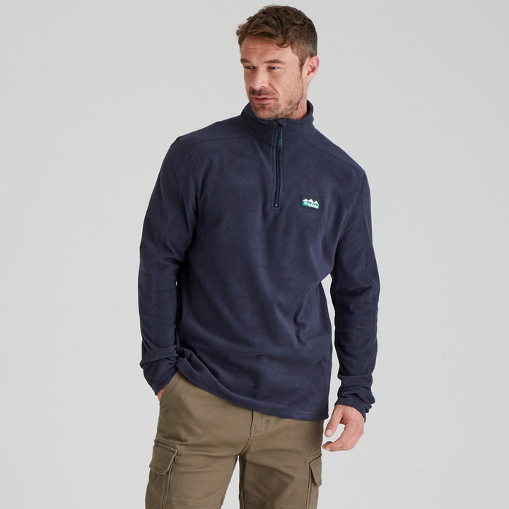 Male model wearing the Ridgeline Narvik fleece in navy with tan cargo trousers, front view cropped at the hip, one hand tucked into a pocket.