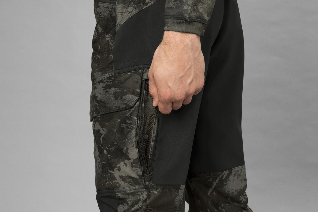 Left-side detail with the model's hand at the mesh-vented thigh cargo pocket, black knee panel visible below