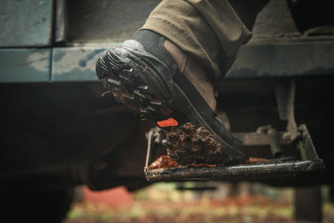 Hand knocking mud off the sole of the Seeland Enduro Explore Mid boot outdoors