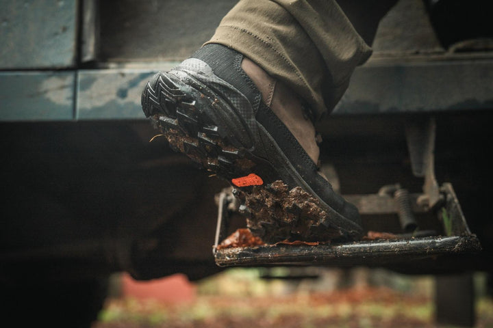 Hand knocking mud off the sole of the Seeland Enduro Explore Mid boot outdoors