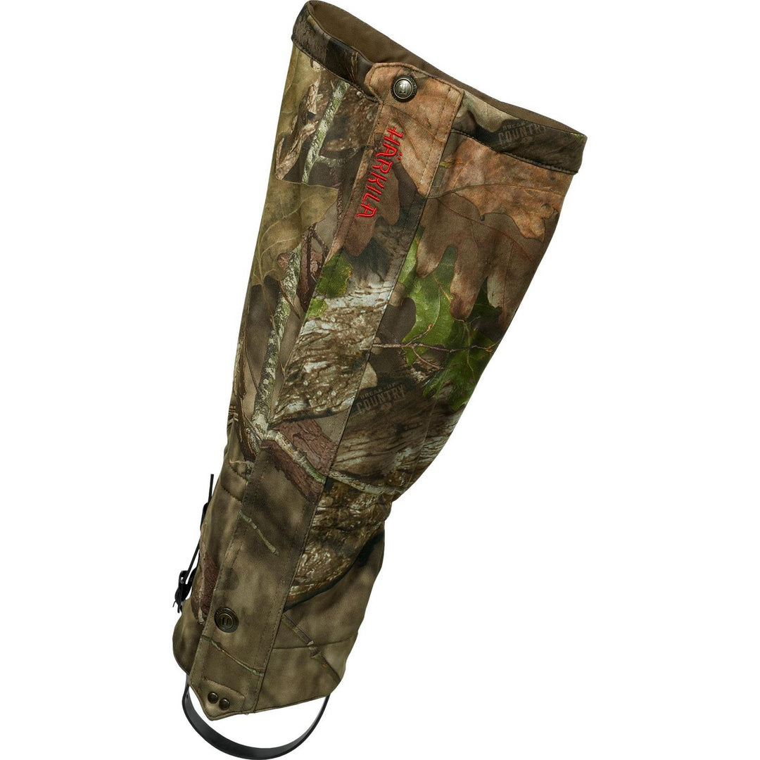 Single Harkila Moose Hunter 2.0 gaiter in Mossy Oak Break-up Country camo, outer side view with the red Harkila logo, press studs and under-boot strap.