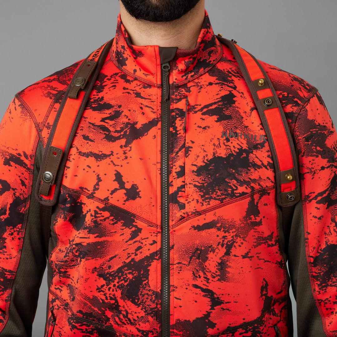 Härkila Wildboar Pro sling on a hunter in a blaze camo jacket, front view showing both padded shoulder straps and the press-stud fastenings.