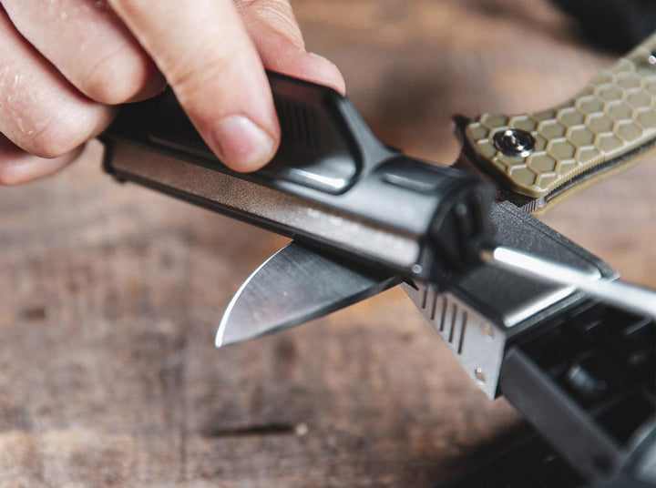 Lifestyle close-up of a hand using a Work Sharp Precision Adjust Elite rod to sharpen a clamped knife blade