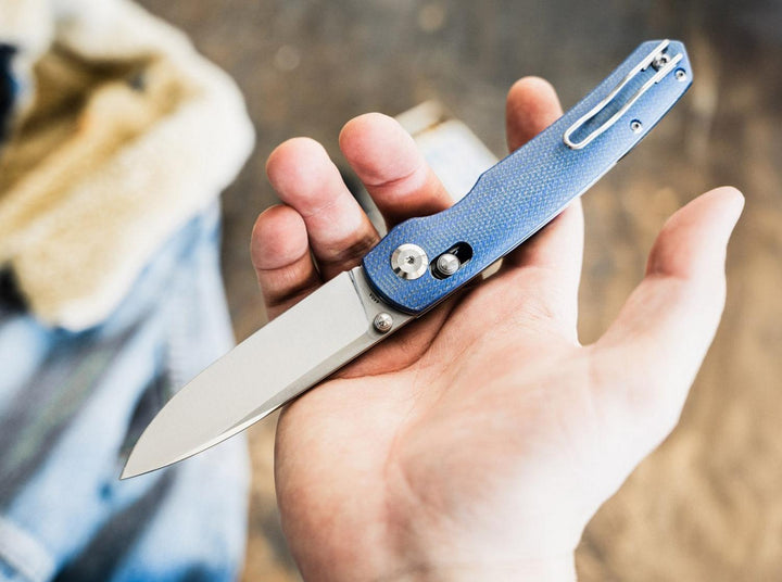 Hand holding the blue Böker Magnum Shango folding knife open, lifestyle shot