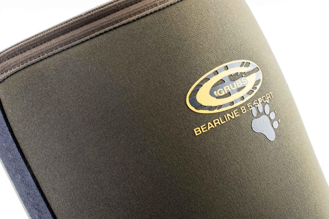 Close-up of the gold Grubs Bearline 8.5 Sport logo and paw print on the olive green neoprene shaft