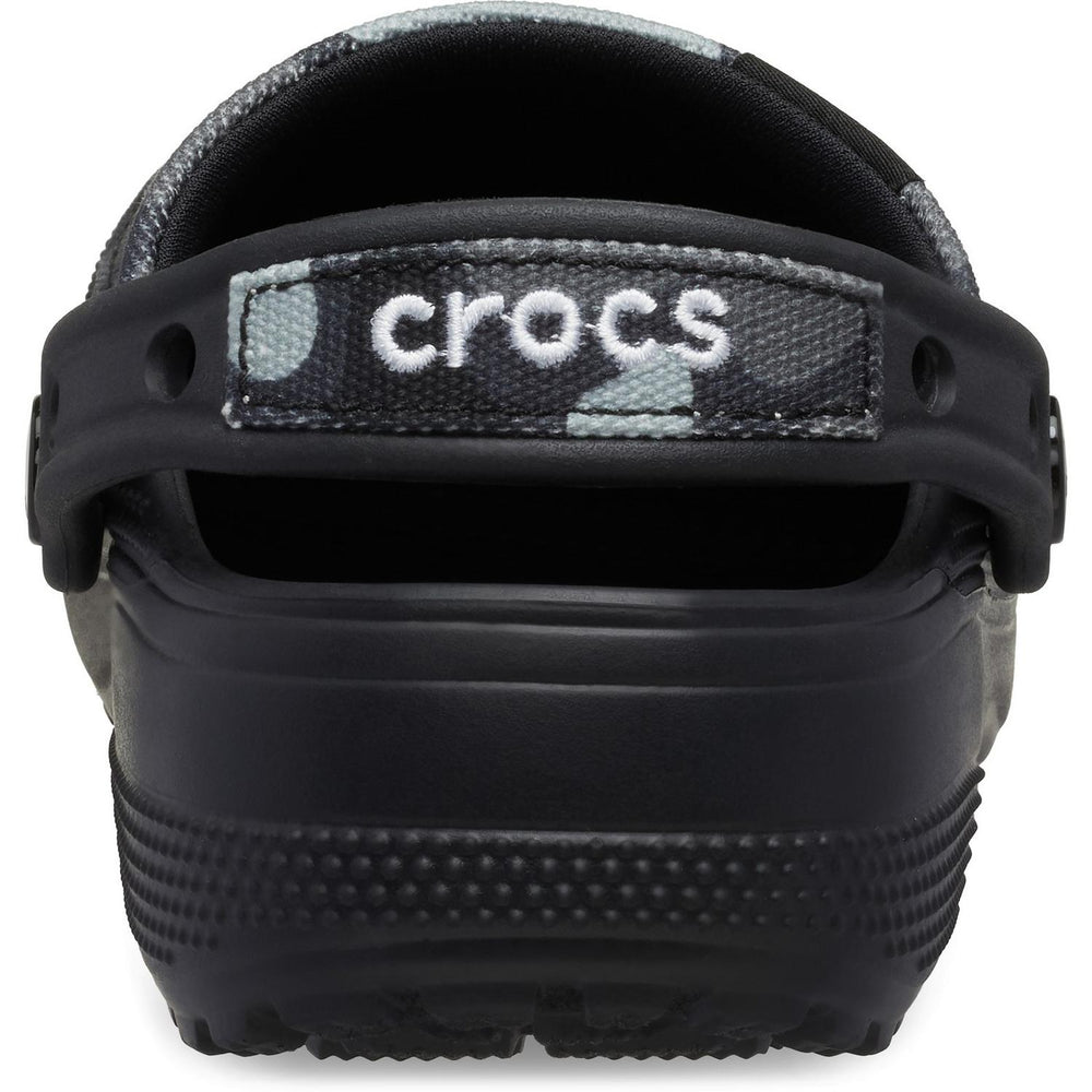 Rear close-up of the black camo Crocs clog, showing the CROCS wordmark on the heel strap over a camo-printed backing