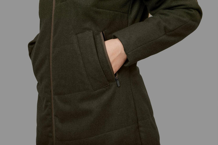 Detail of the Härkila Metso Winter jacket: a hand slipped into the deep zipped hand-warmer pocket on the hip.