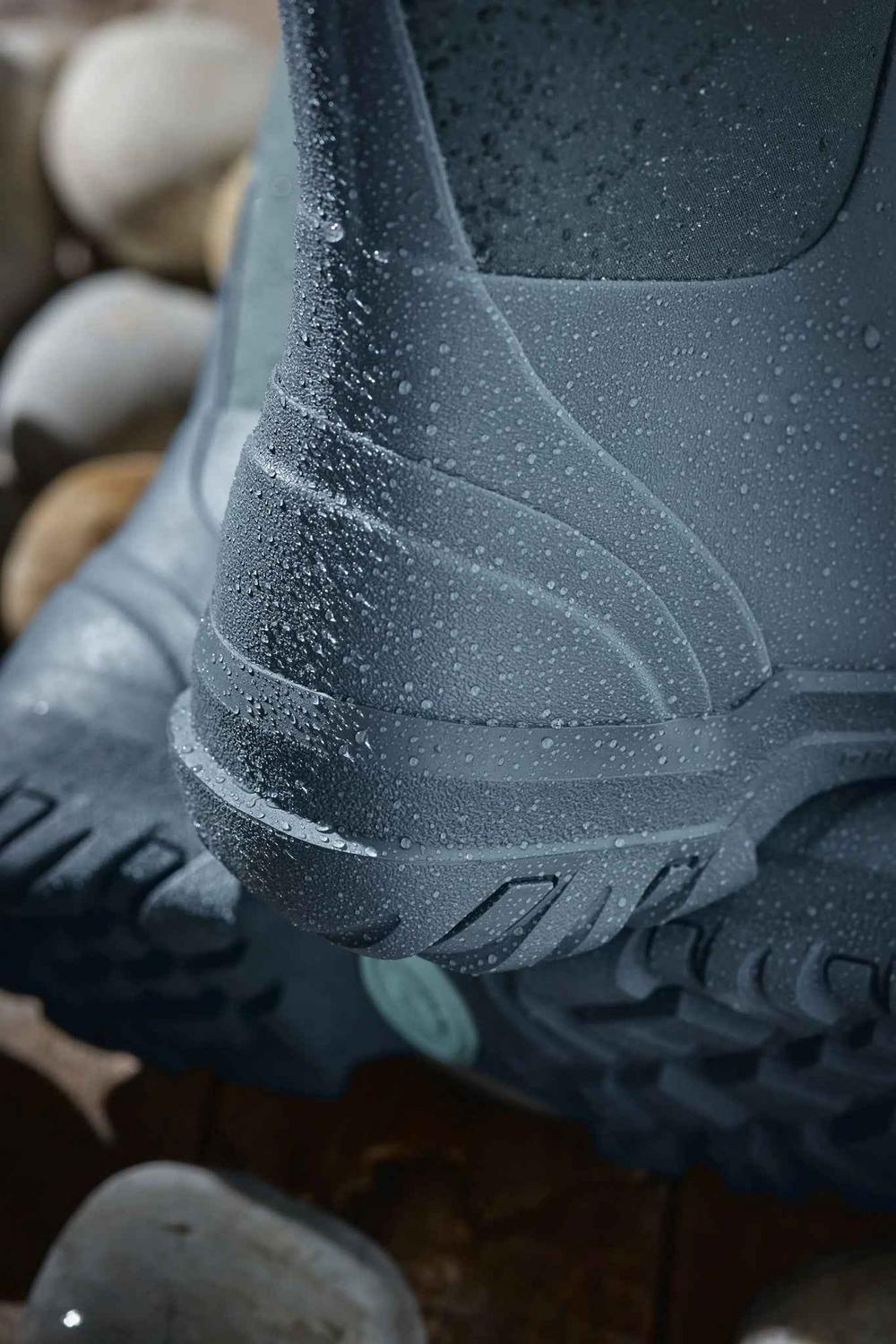 Close-up of the heel and lower shaft of a grey Grubs Frostline 5.0 boot covered in water droplets on pebbles