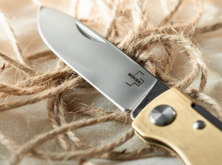 Close-up of the Böker Plus Atlas Brass blade and brass handle on twine, lifestyle shot
