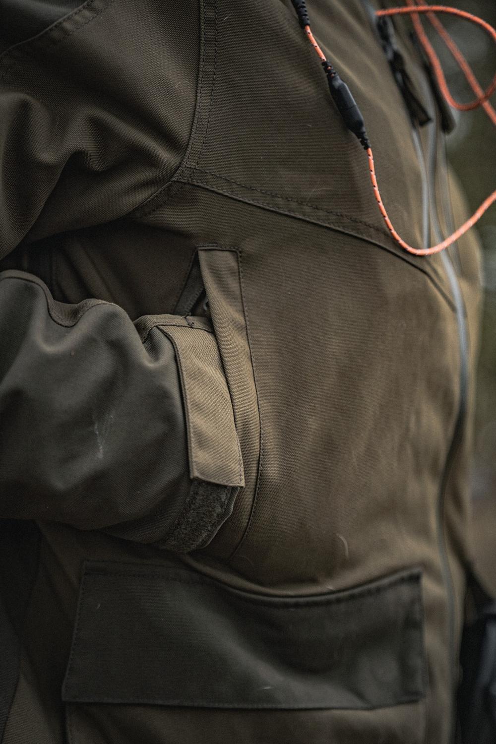 Detail of the Seeland Trax jacket chest and hip, showing the orange hood drawcord, flapped chest pocket and large bellows hip pocket