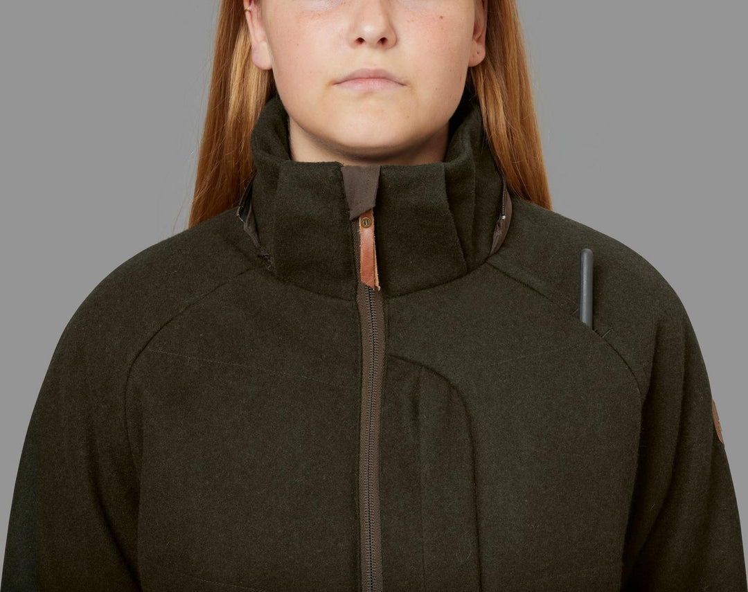 Close-up of a model in the Härkila Metso Winter jacket with the collar zipped high, showing the copper zip pull and a grey reflective tab on the chest.
