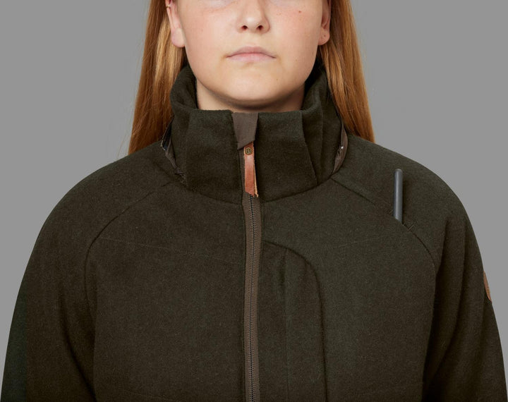 Close-up of a model in the Härkila Metso Winter jacket with the collar zipped high, showing the copper zip pull and a grey reflective tab on the chest.
