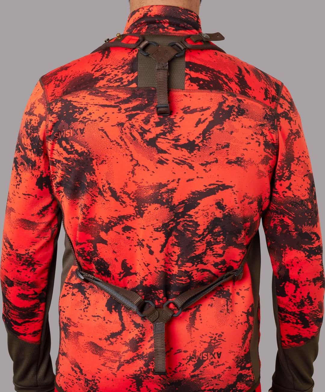 Härkila Wildboar Pro sling worn as a harness over a blaze camo jacket, viewed from behind showing the shoulder yoke and the strap across the back.