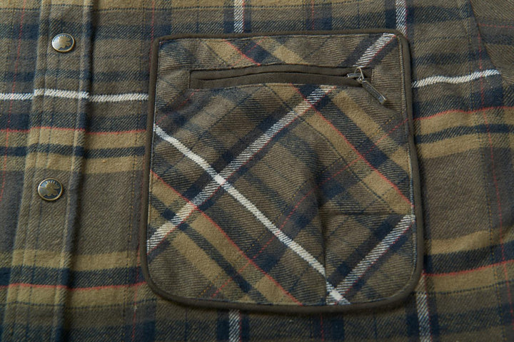 Close-up of a Harkila Pajala chest pocket with a horizontal zip across the flap, flanked by two press studs on the check flannel.