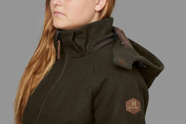 Model wearing the Härkila Metso Winter jacket, three-quarter view of the shoulder and high collar with the hexagonal leather Härkila badge on the hip.