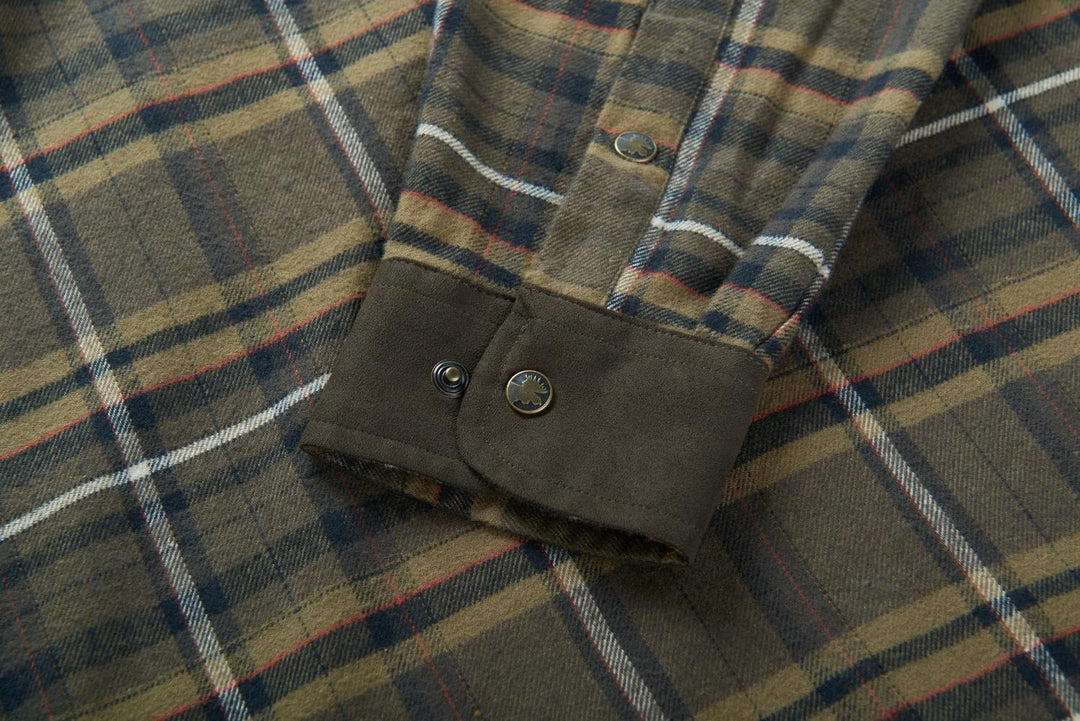 Close-up of the Harkila Pajala shirt cuff, a dark green two-button adjustable cuff against the olive check sleeve.