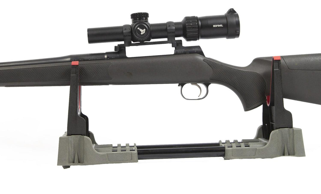 Mjoelner foldable gun cleaning bench in use, a bolt-action rifle with a scope resting in the grey cradle, side view