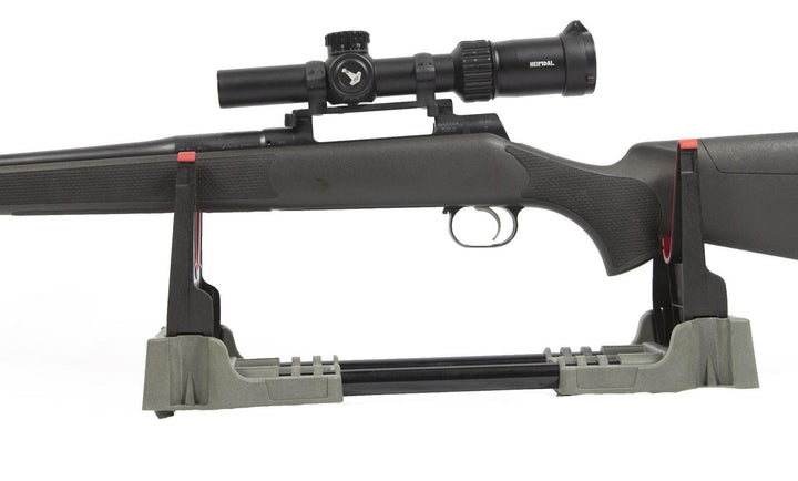 Mjoelner foldable gun cleaning bench in use, a bolt-action rifle with a scope resting in the grey cradle, side view