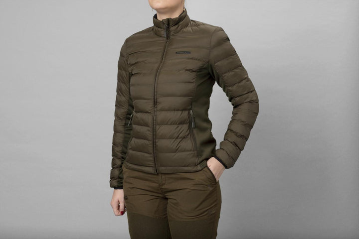 Model wearing the olive Seeland Therma Puffer Jacket zipped up, three-quarter front view with hands in the pockets, plain grey studio backdrop.