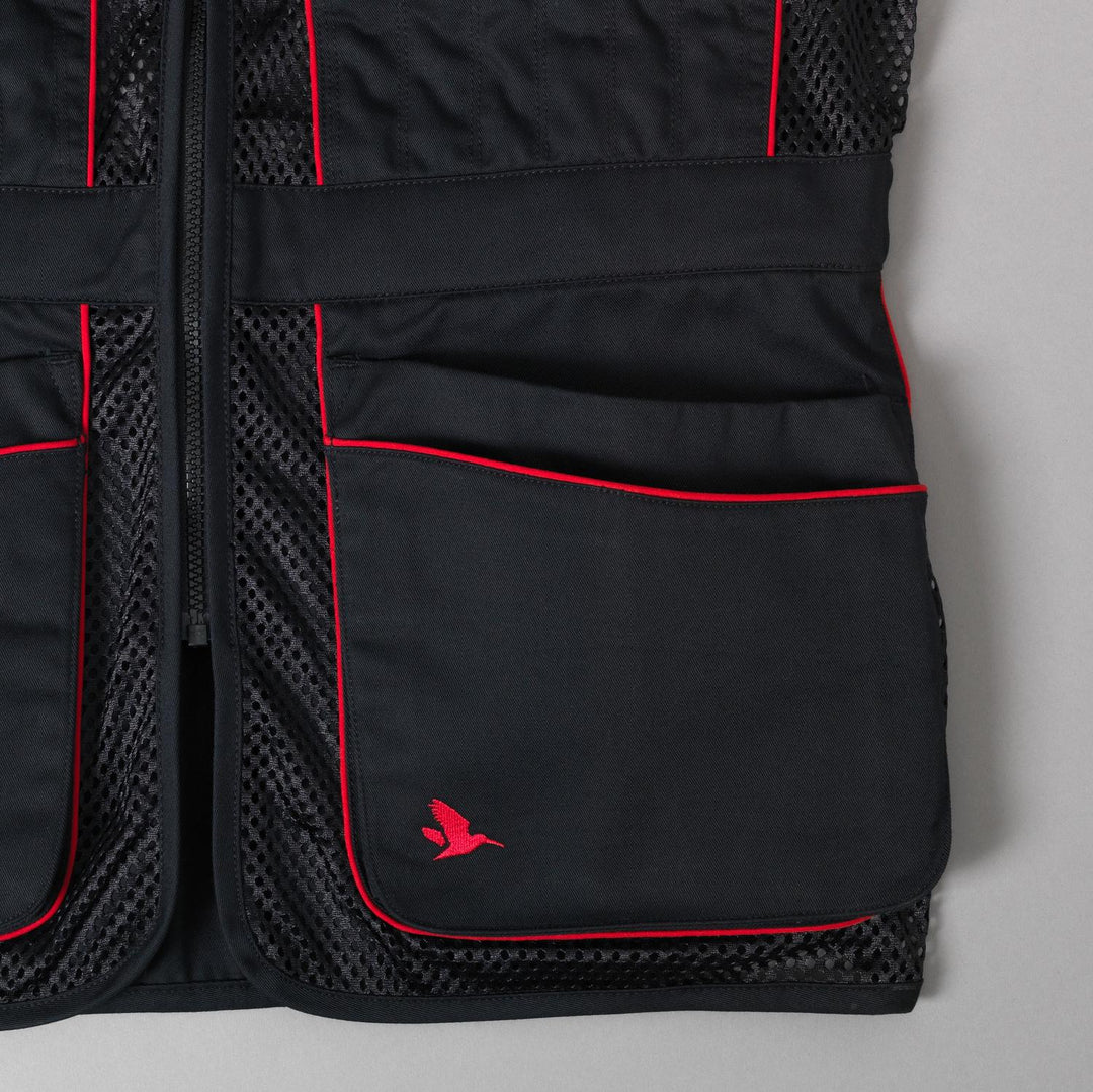 Close-up of the lower front pockets, red trim and the red Seeland flying-bird logo on the black twill