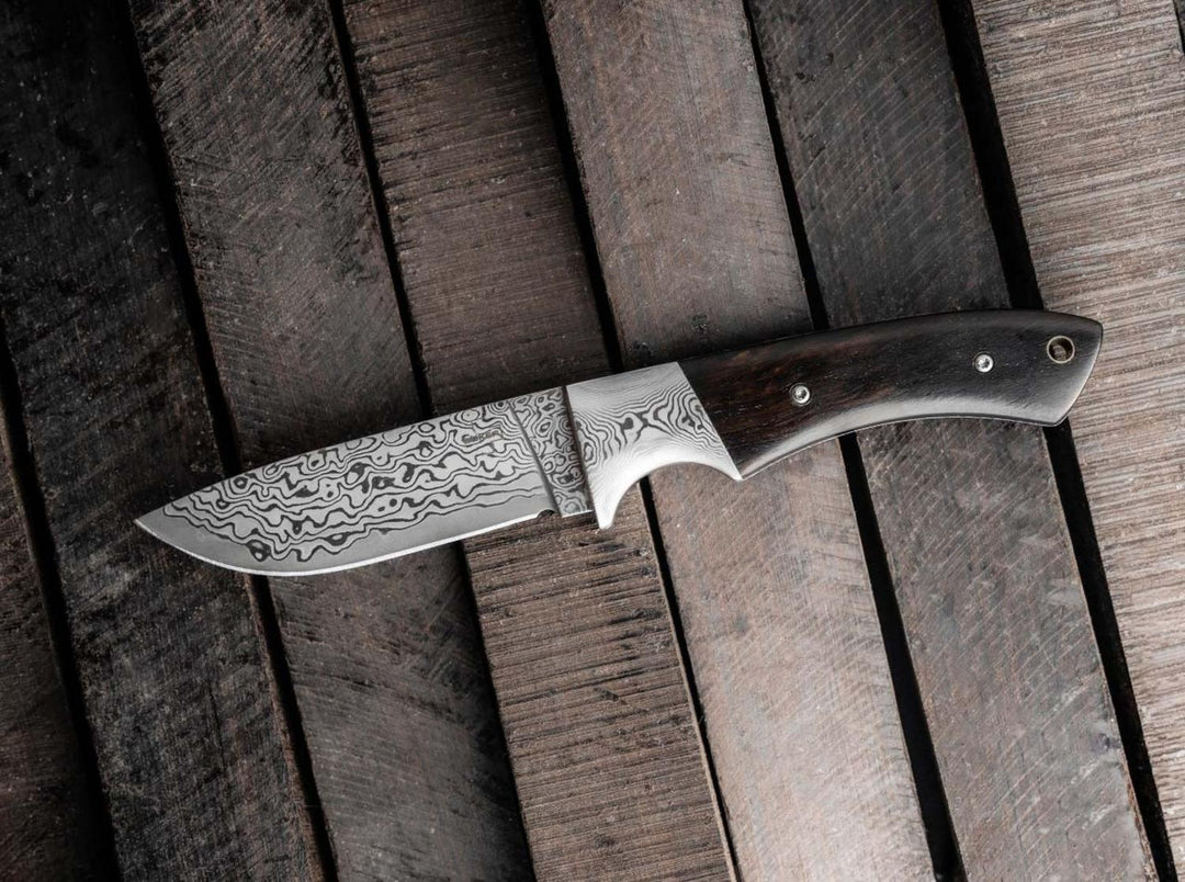 Böker Plus M-One Damascus fixed blade hunting knife lying on rustic dark wooden planks, lifestyle shot