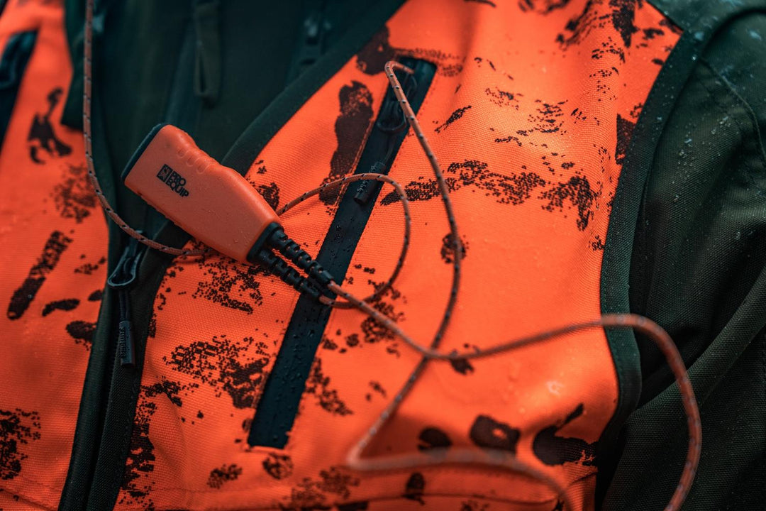Close-up of the Seeland Trax Blaze waistcoat chest with an orange game call clipped to the zipped pocket.