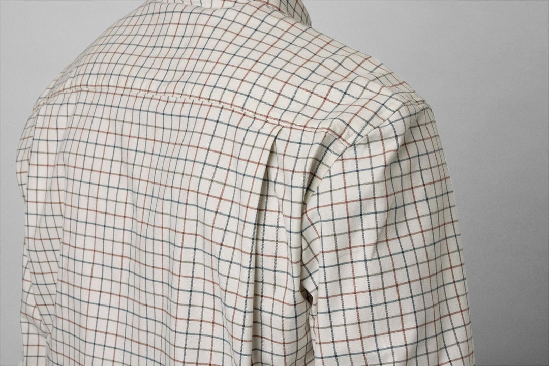 Over-shoulder fabric close-up of the Oxford shirt showing the cream, red and dark check weave and shoulder seam