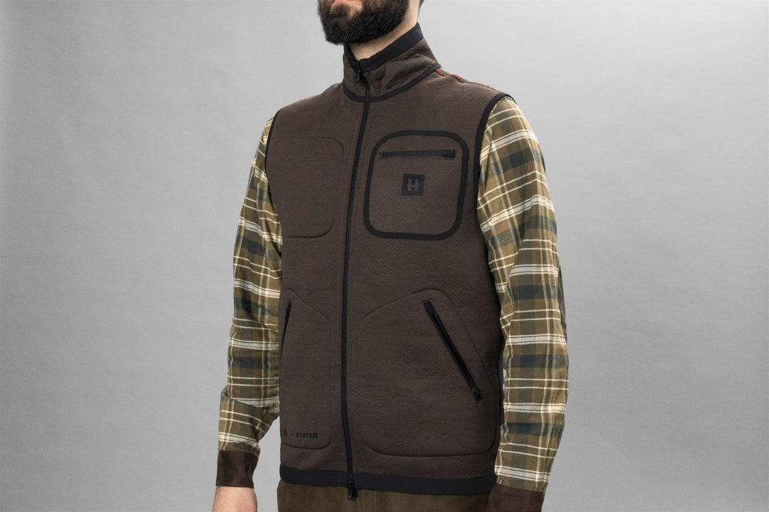 Man wearing the brown side of the Härkila Kamko Pro Edition reversible waistcoat over a checked shirt