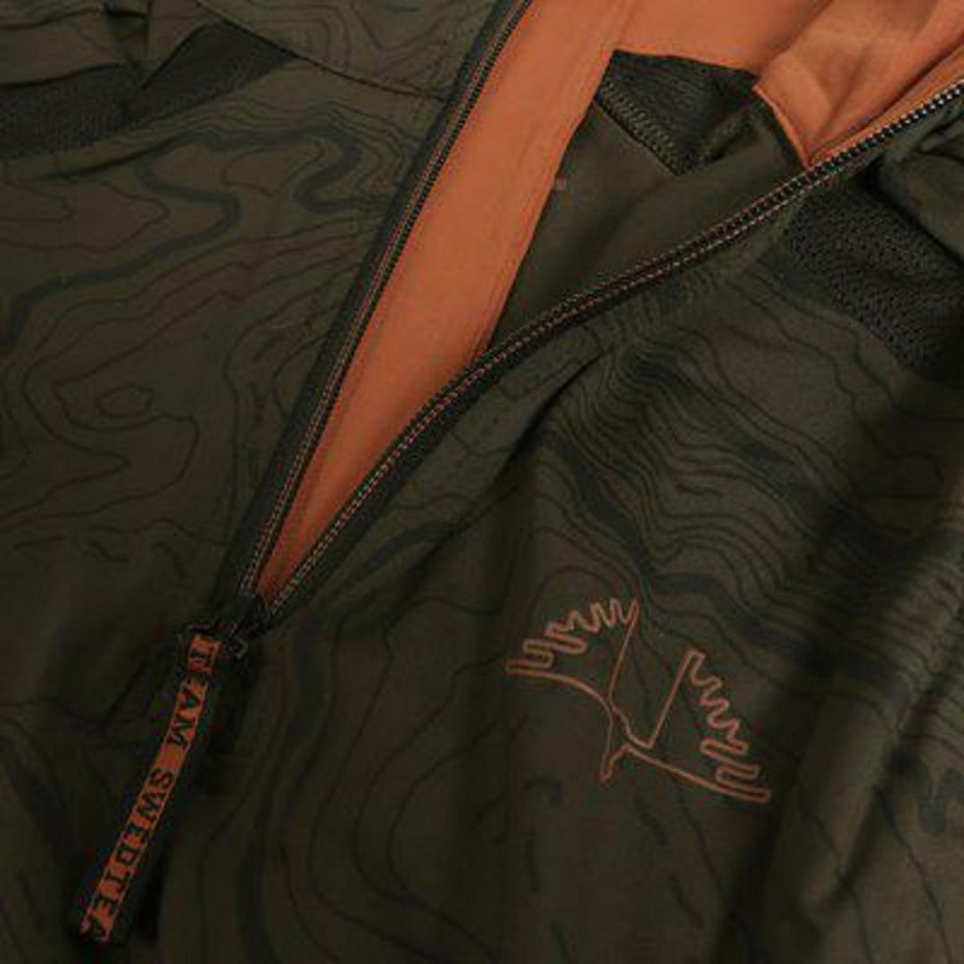 Close-up of the olive Alpha Antibite sweater, the orange quarter-zip open beside the embroidered SwedTeam bird logo
