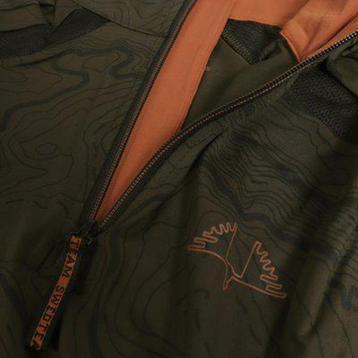 Close-up of the olive Alpha Antibite sweater, the orange quarter-zip open beside the embroidered SwedTeam bird logo