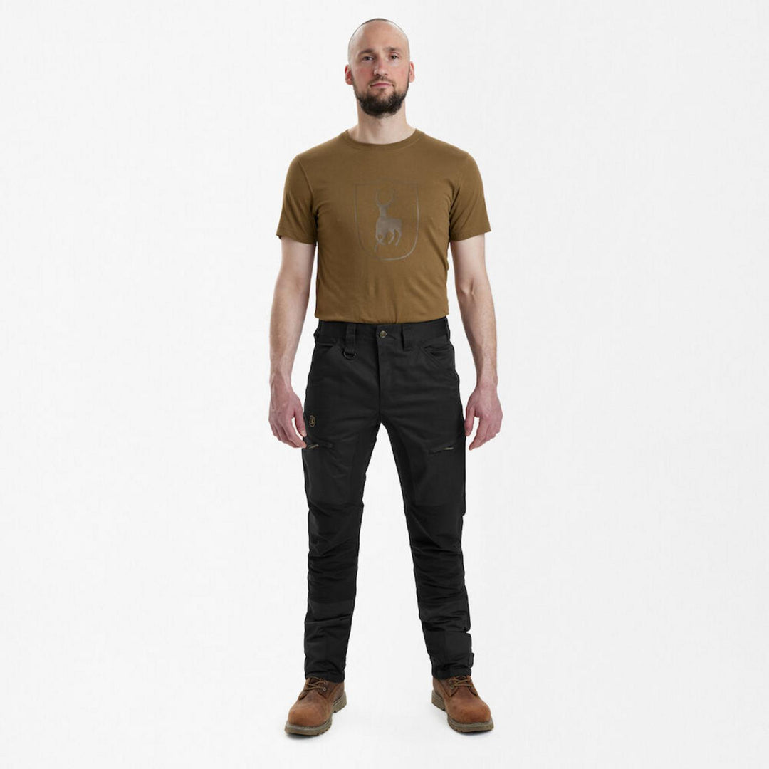 Full-length front view of a model wearing Deerhunter Rogaland Stretch Trousers Contrast Black with a tan Deerhunter branded t-shirt