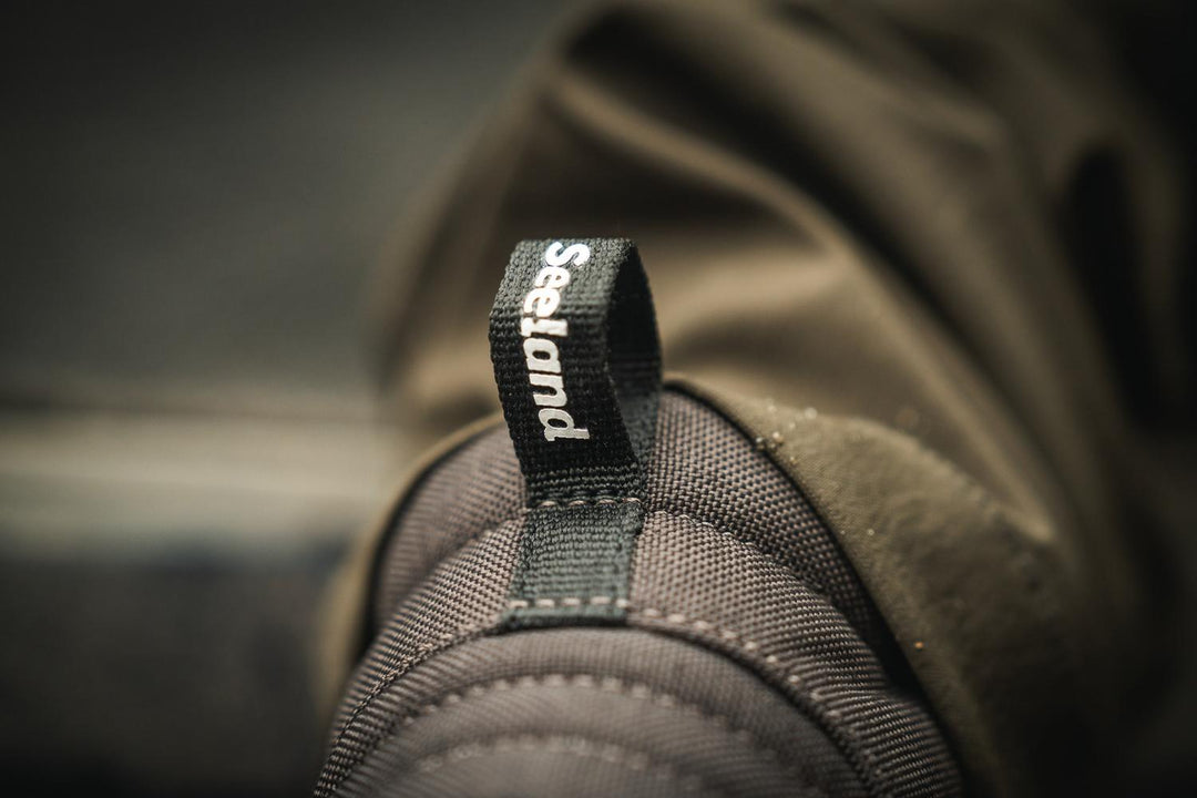 Close-up of the heel pull loop labelled 'Seeland' on the Enduro Explore Mid boot, worn with trousers tucked in