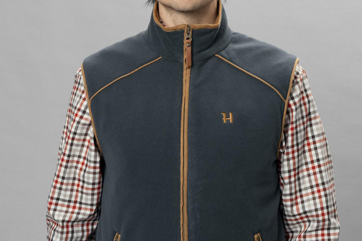 Close-up front view of a model in the dark navy Härkila Sandhem 200 waistcoat over a red check shirt