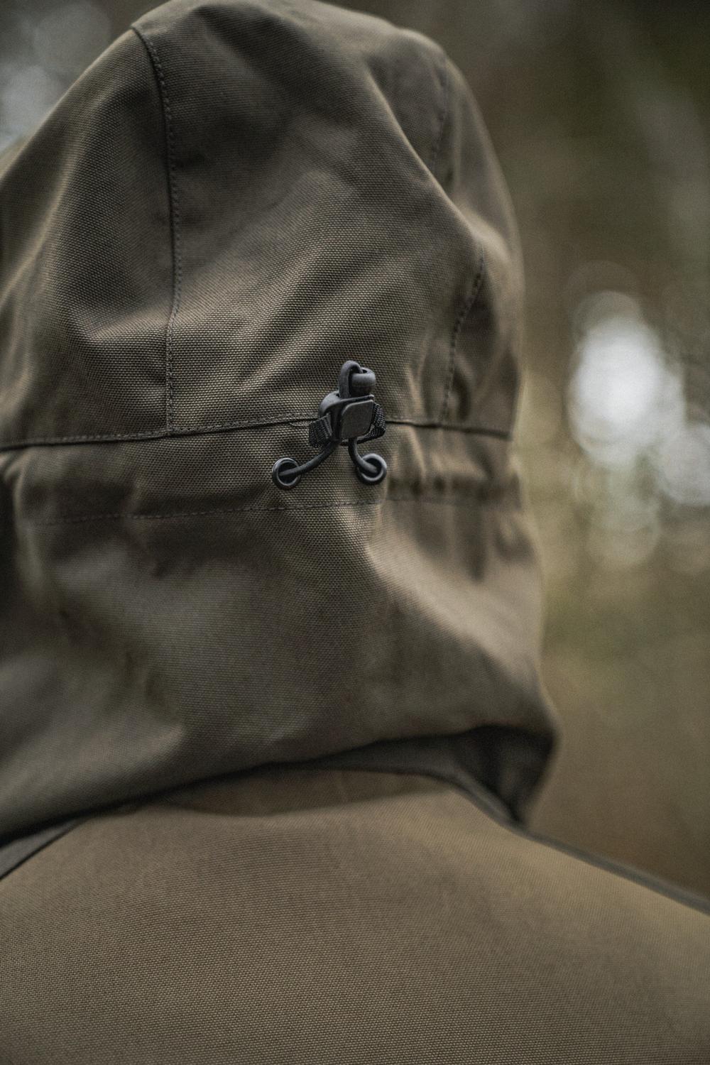 Close-up of the Seeland Trax jacket hood worn up, showing the black cord-lock volume adjuster at the side of the hood
