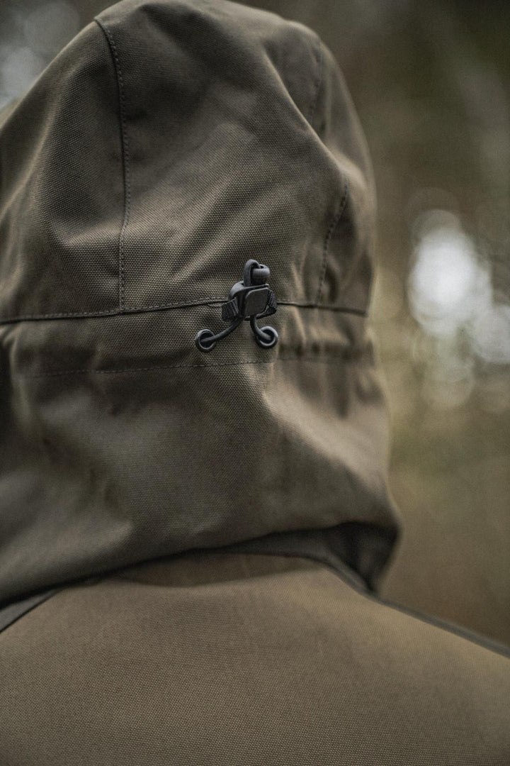 Close-up of the Seeland Trax jacket hood worn up, showing the black cord-lock volume adjuster at the side of the hood