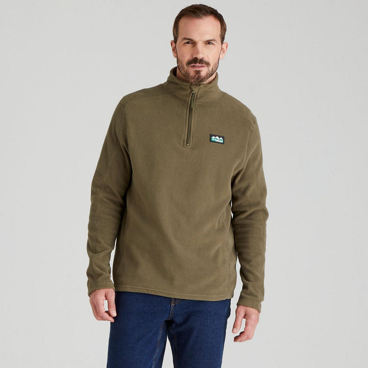 Male model wearing the Ridgeline Narvik fleece in olive with blue jeans, front view cropped at the hip, showing the soft fleece drape and chest badge.