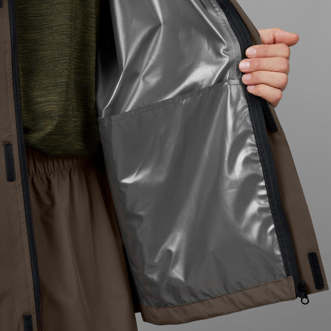 Jacket held open to show the silver taped-seam inner lining and zip, worn over an olive marl base layer
