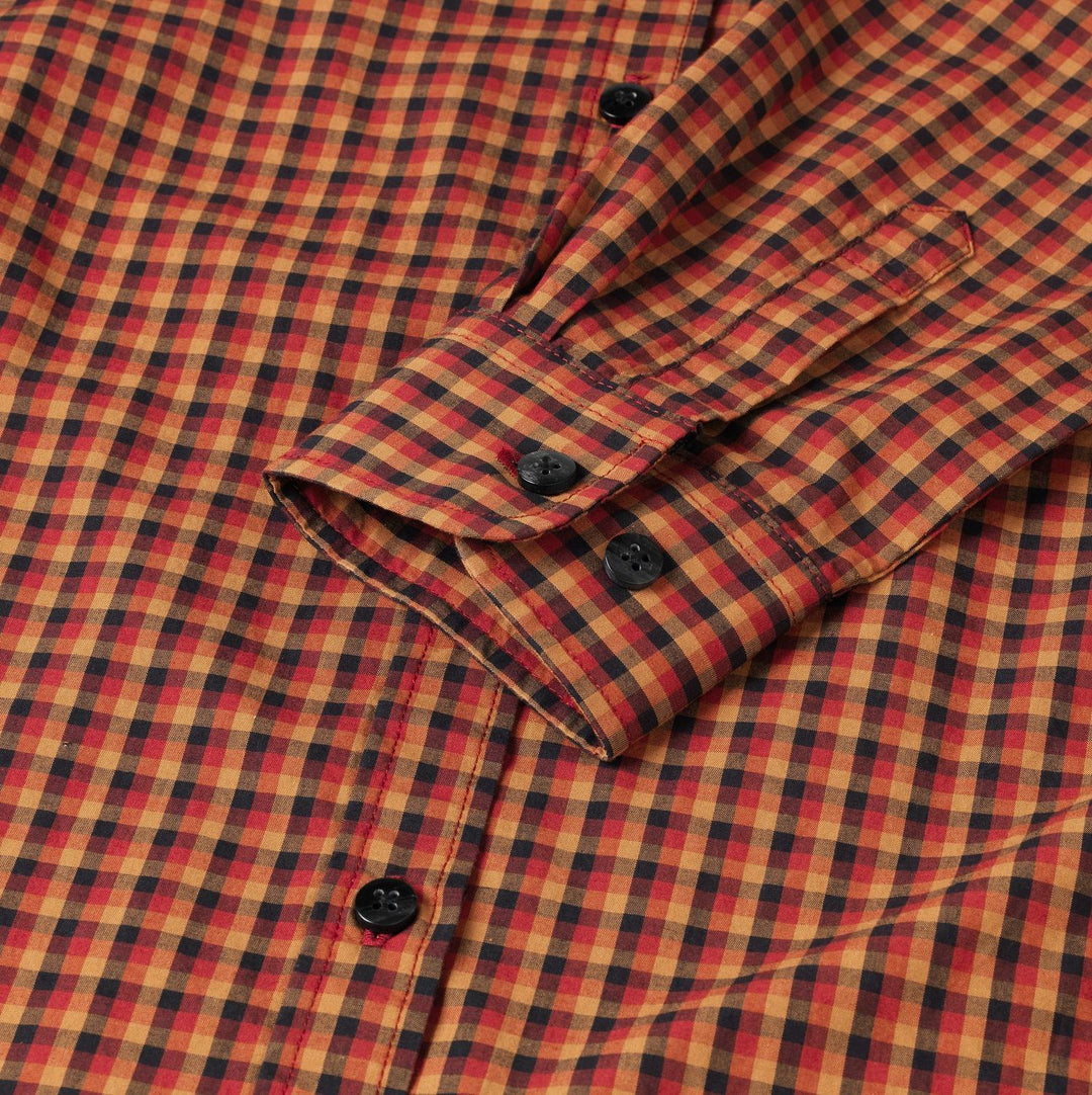 Close-up of the Harkila Selja shirt cuff, showing the two-button adjustable cuff and the fine red, orange and navy check weave.