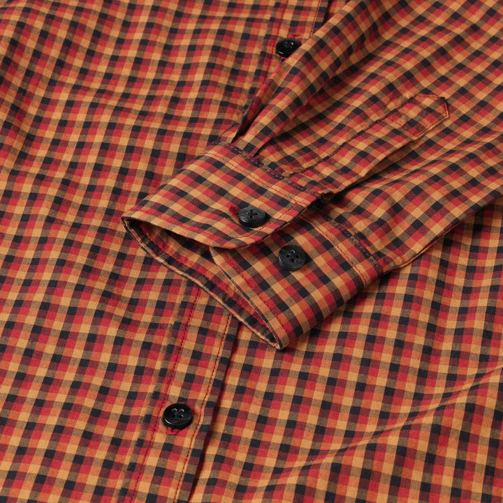 Close-up of the Harkila Selja shirt cuff, showing the two-button adjustable cuff and the fine red, orange and navy check weave.