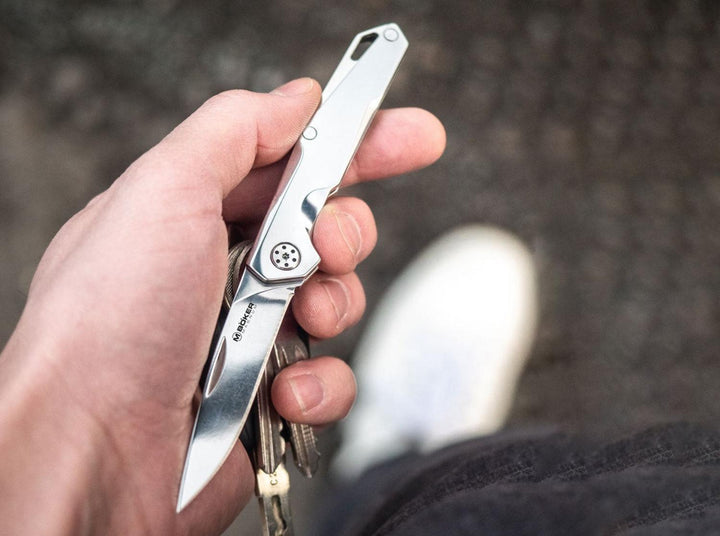 Hand holding the slim Böker Magnum Shiny EDC steel folding knife attached to keys, lifestyle shot