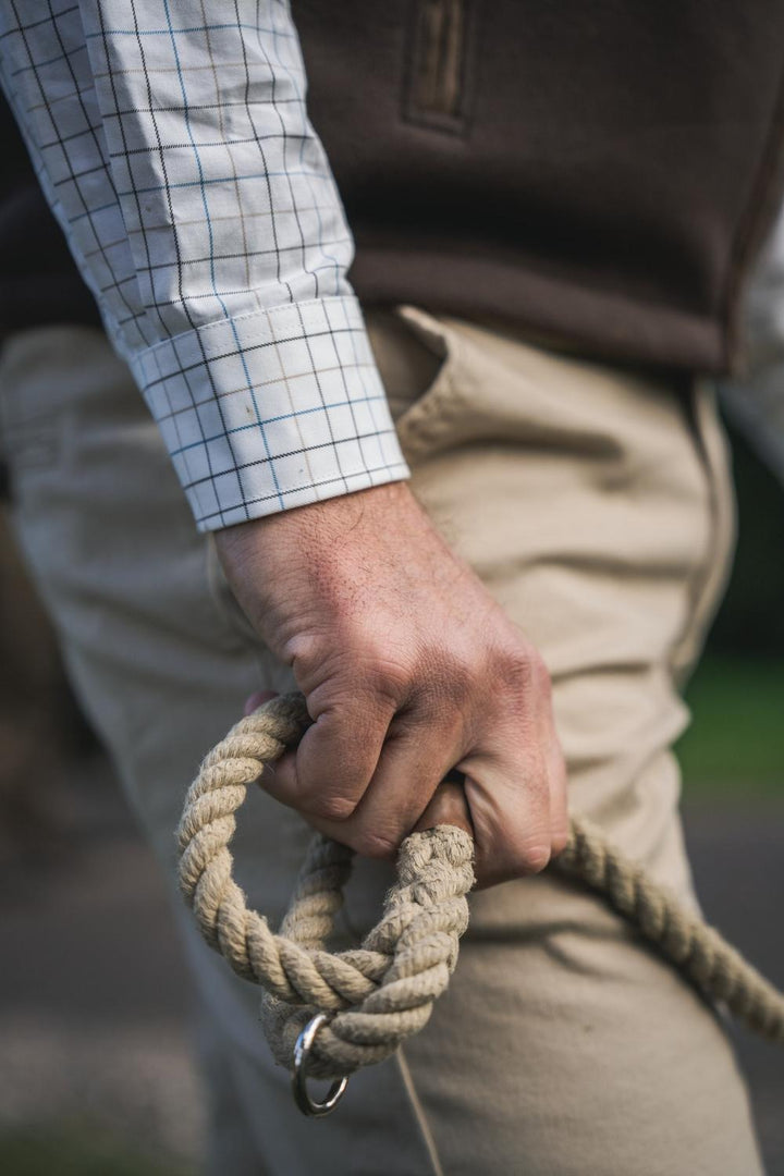 Harkila Norberg Chinos beige – view 9: lifestyle shot of the wearer's hand holding a coiled rope with the chinos and gilet in view.