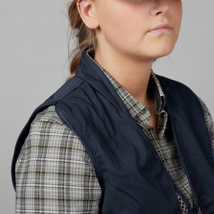 Model wearing the Seeland Skeet II Lady waistcoat, head-and-shoulder view showing the navy shoulder shooting panel over a check shirt