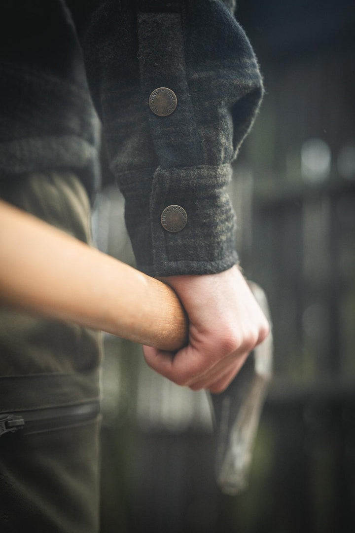 Close-up of the buttoned cuff on the sleeve of the Seeland Canada Yukon jacket as the wearer grips an axe